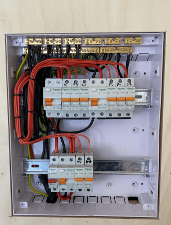 A traditional household switchboard with exposed red and green wiring