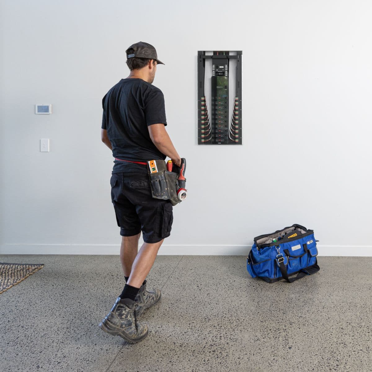 A Basis-trained electrician stepping back from a freshly mounted Basis Board on the wall.